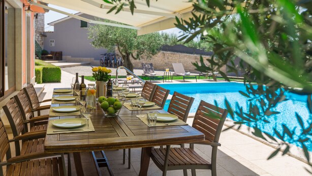 An outdoor dining area with a pool in the background. - Pool, whirlpool, 12 persons, garden, children's playground,bicycles,table tennis (Anžici)