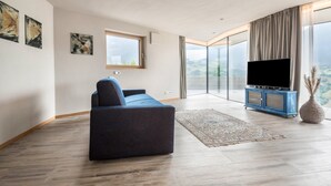 Una sala de estar moderna con un sofá, una televisión y un ventanal con vistas.