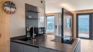 A modern kitchen with a built-in stove, a coffee maker, and a clock on the wall.