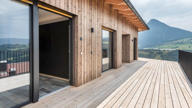 A wooden exterior with large glass doors and a deck.