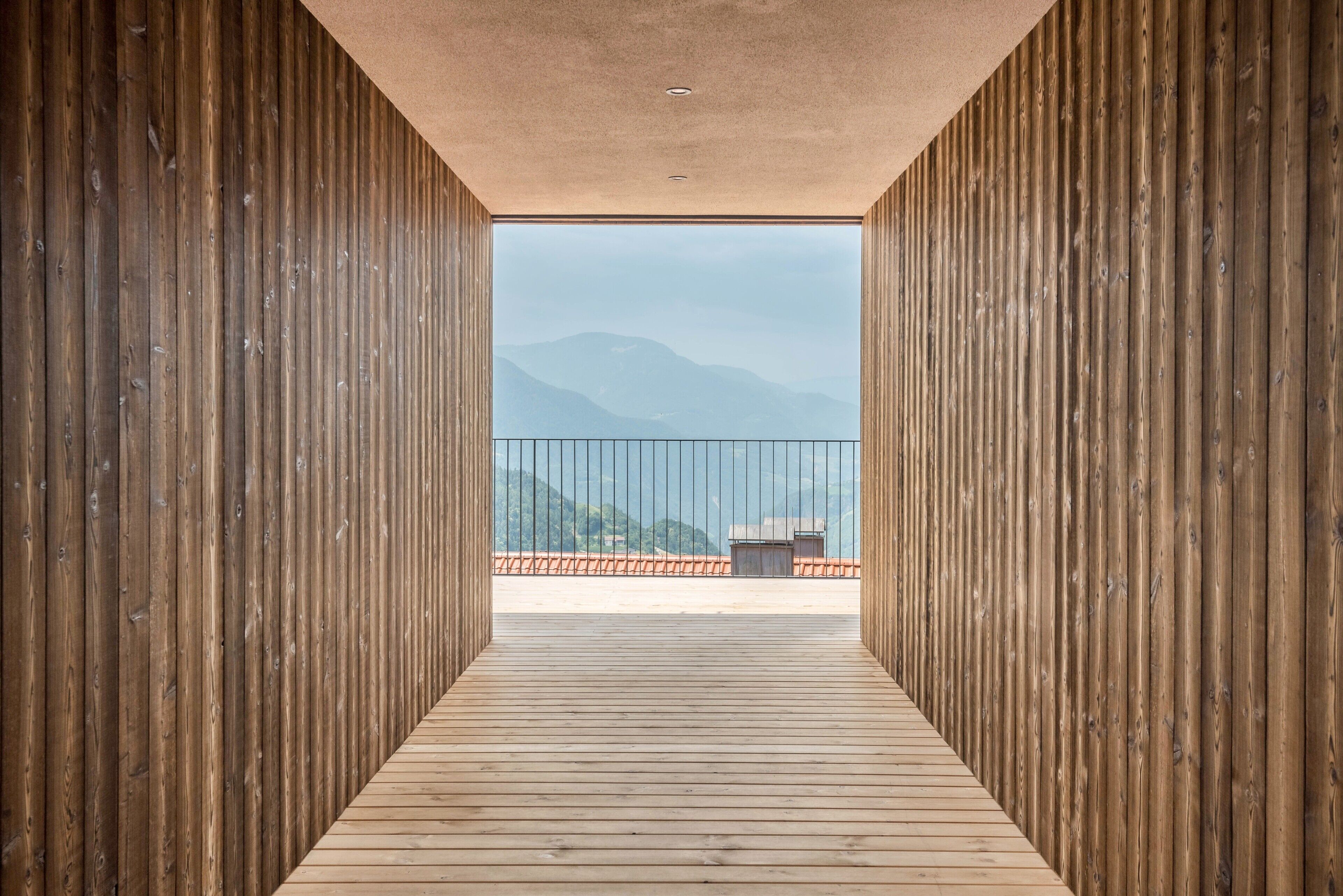 Ein Holzkorridor, der zu einem Balkon mit Bergblick führt.