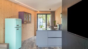 A modern kitchen with a teal refrigerator, white cabinets, and a large window.