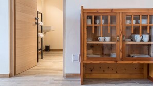 A hallway with a wooden door, a mirror, a sink, and a cabinet with dishes. - 'AUMIA Apartment Rubin' with Mountain View & terrace (Völs)