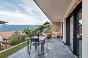 Uma varanda com mesa e cadeiras, um muro de pedra e vista para o campo.