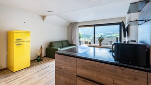 A modern kitchen with a wooden countertop, a yellow refrigerator, and a large window with a view of the outdoors.