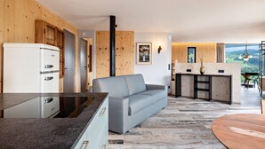 Eine moderne Küche mit einem eingebauten Kühlschrank, einem grauen Sofa und einem Essbereich mit Holztisch und Blick.