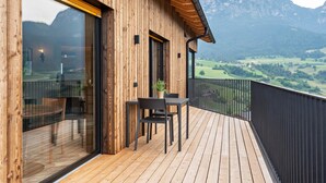 Eine Holzwand mit Balkon, Tisch, Stühlen und einem Blumentopf.