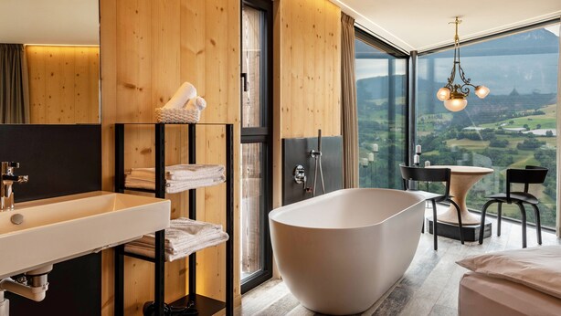 Ein modernes Badezimmer mit freistehender Badewanne, einem großen Spiegel und einer Holzvertäfelung.