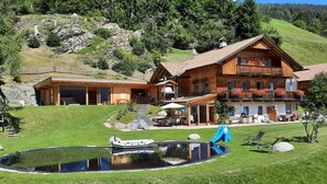 Una cabaña de madera con balcón, piscina y un pequeño bote.