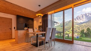 Cocina moderna con comedor, ventanas amplias y vistas a la montaña, y piso de madera.