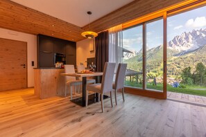 Une cuisine moderne avec un coin repas, de grandes fenêtres offrant une vue sur les montagnes et un plancher en bois.