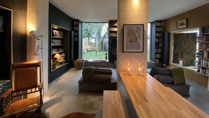 A modern living room with a wooden coffee table, a leather chair, and a bookshelf.