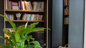 A cozy living room with a bookshelf, a large plant, and a woven basket.