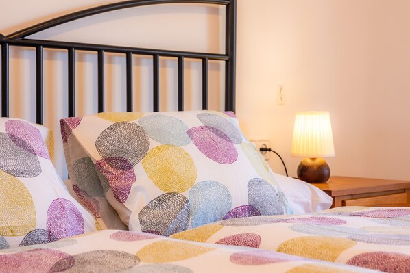 Un lit avec des oreillers aux motifs colorés et une lampe de chevet.