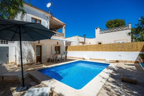 A swimming pool with a tiled deck, a patio area with a table and chairs, and a wooden fence. - Villa Balena with Private Pool, Sea Views, Wi-Fi, and Air Conditioning (Sa Ràpita)