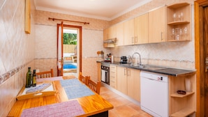 Een keuken met houten kastjes, een vaatwasser en een eettafel met placemats.