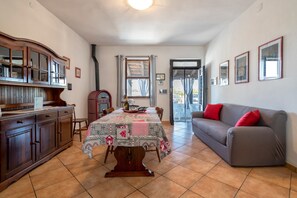 A dining area with a table set for four, a sofa, a cabinet, and a window with curtains.