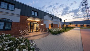 Un bâtiment moderne avec une façade en briques, de grandes fenêtres et une entrée bien éclairée.