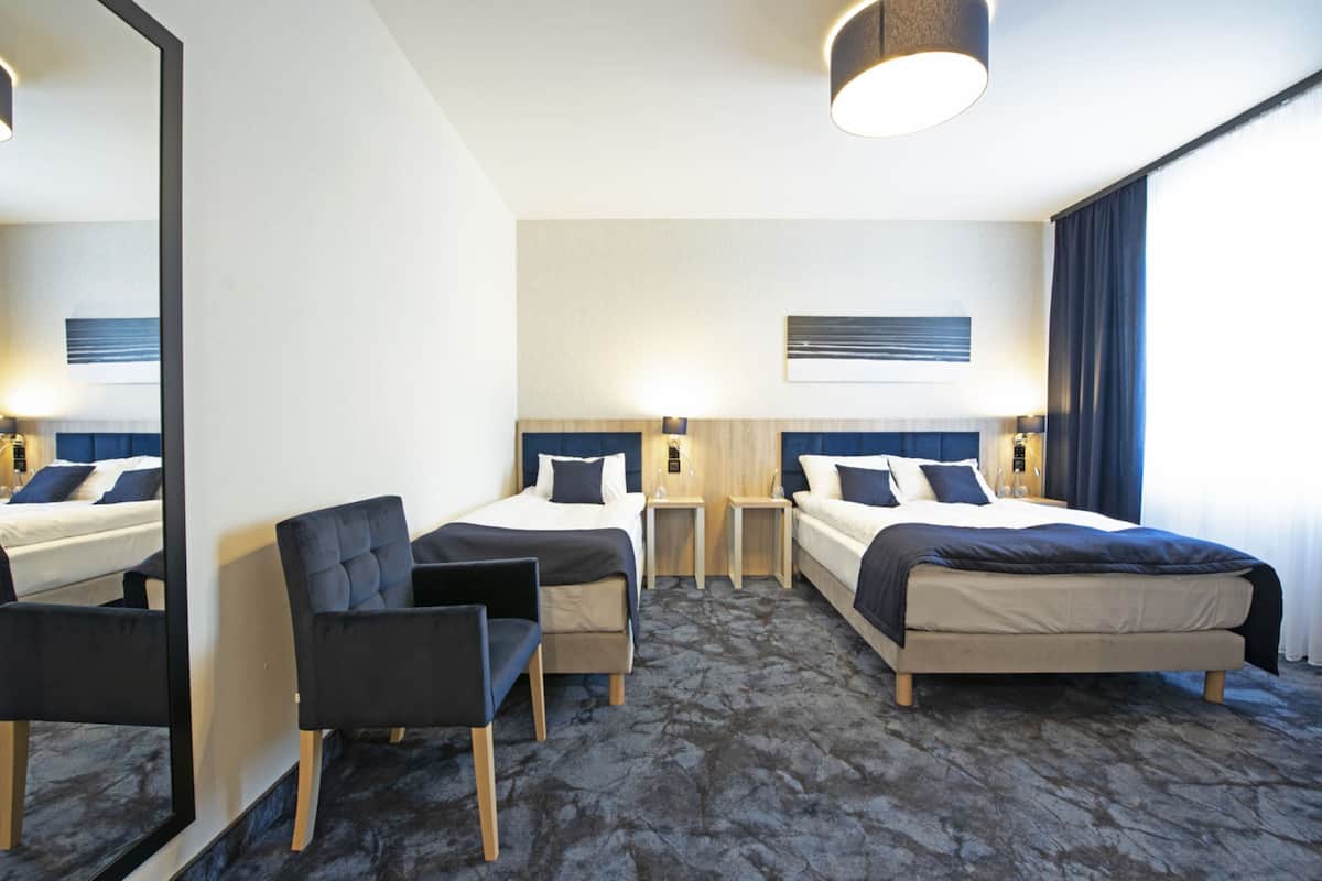 Een hotelkamer met twee bedden, een bureau, een stoel, een spiegel en een groot raam.