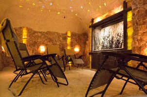 Une pièce aux murs de pierre, avec une cheminée et plusieurs chaises pliantes.