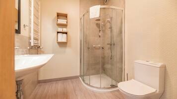 Un baño moderno con ducha de vidrio, lavamanos blanco y retrete.