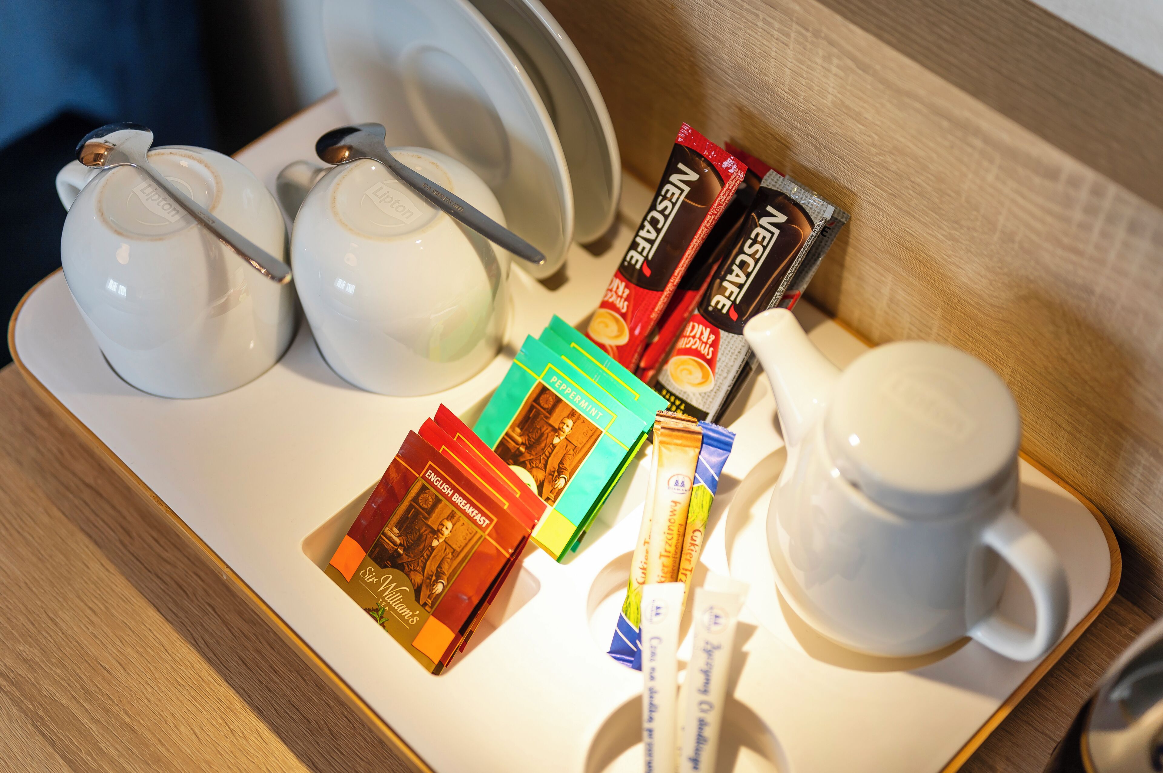 Una bandeja con tetera, taza y diversos alimentos para el desayuno, incluyendo libros y aperitivos.