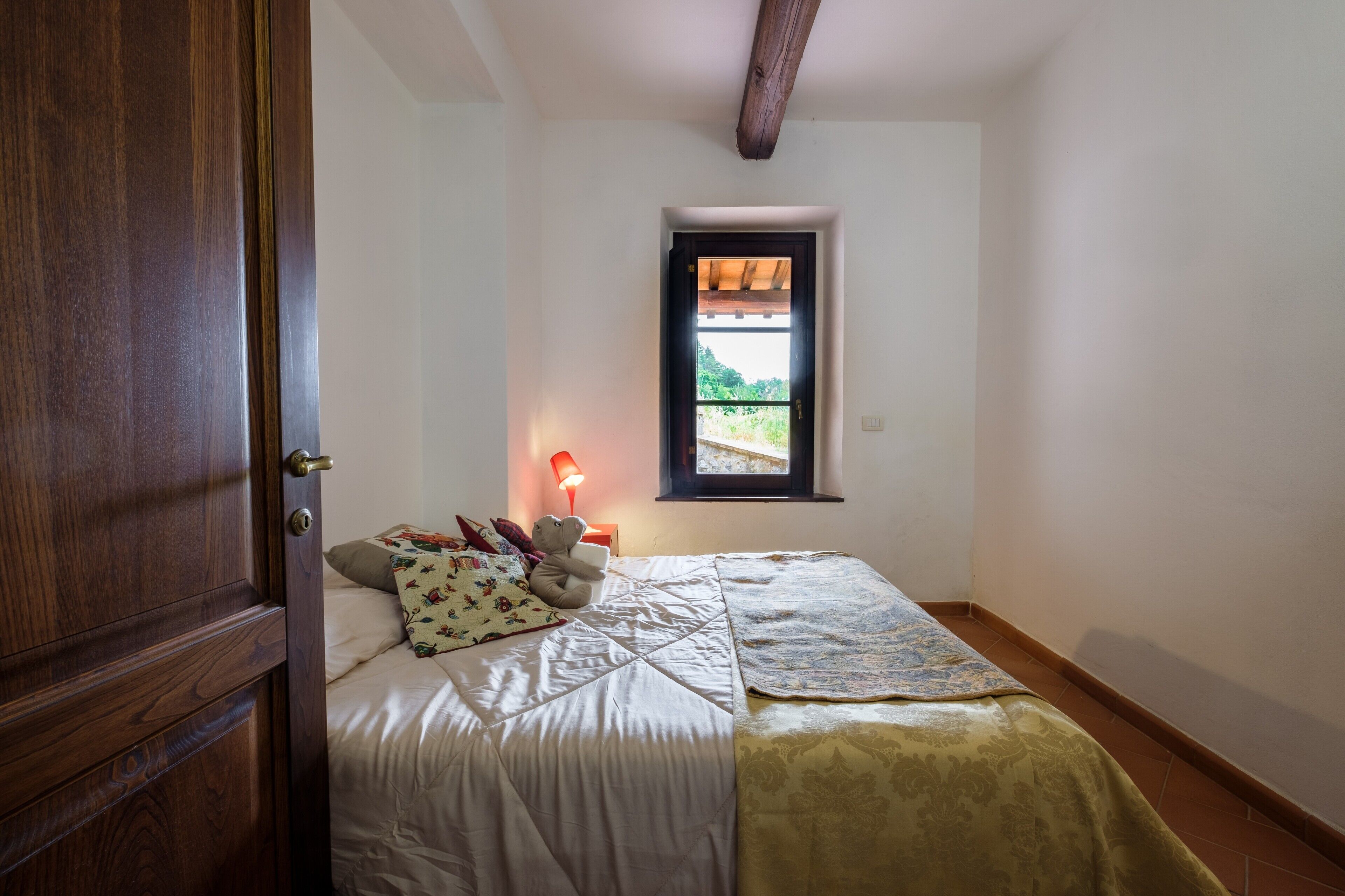 Una camera da letto con un letto, una finestra, una porta e un comodino con una lampada.