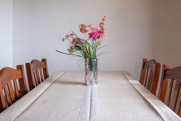 Une table à manger ornée d’un vase de fleurs, entourée de chaises en bois.