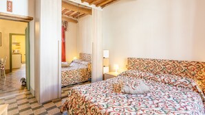 Une chambre à coucher comprenant un lit, un miroir, une table de chevet et une porte donnant sur une salle de bain.