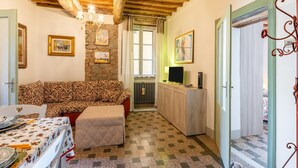 Une pièce chaleureuse avec un canapé à motifs, une table à manger dressée, un téléviseur et un mur en pierre.
