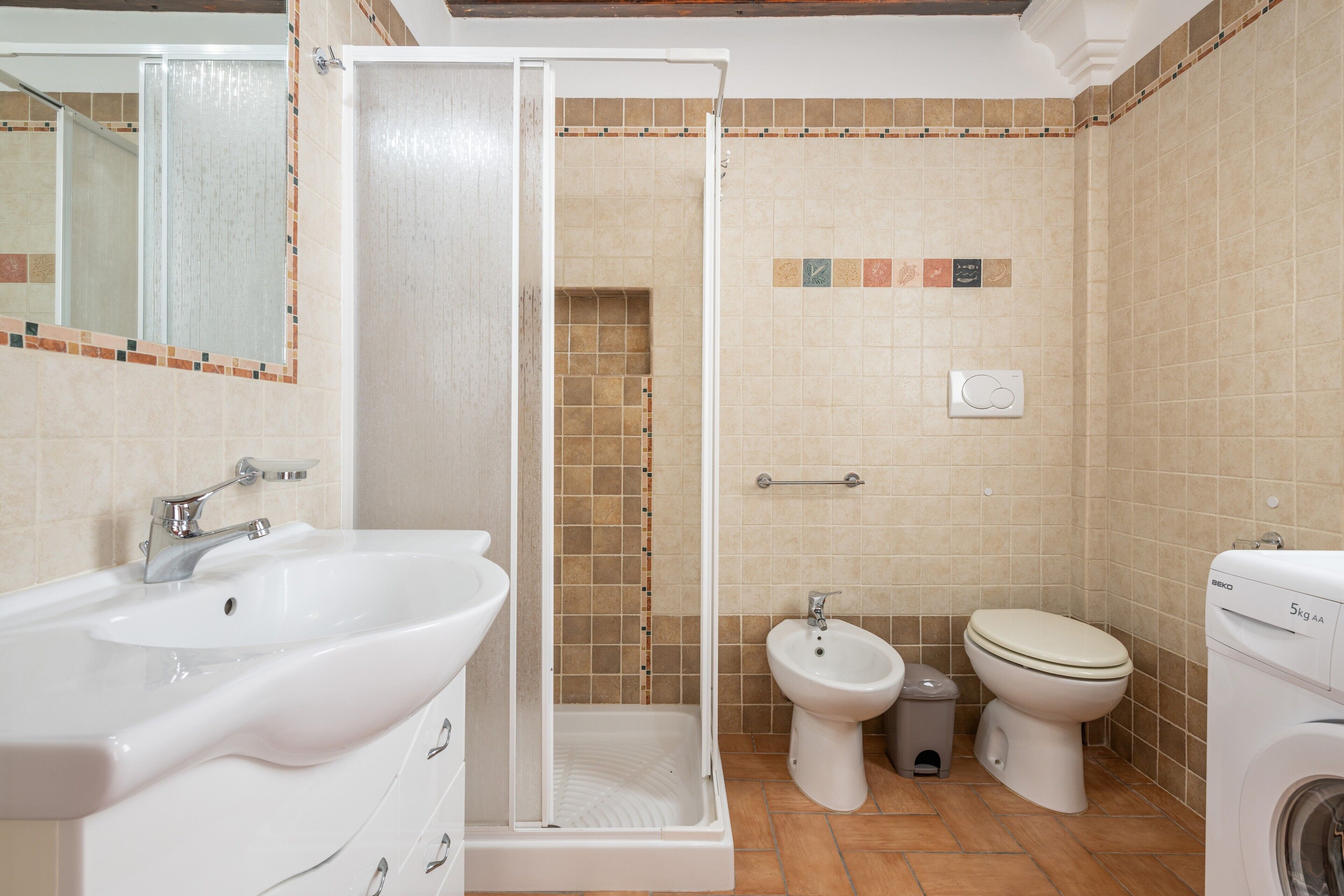Een badkamer met douche, wastafel, toilet, bidet en een wasmachine.
