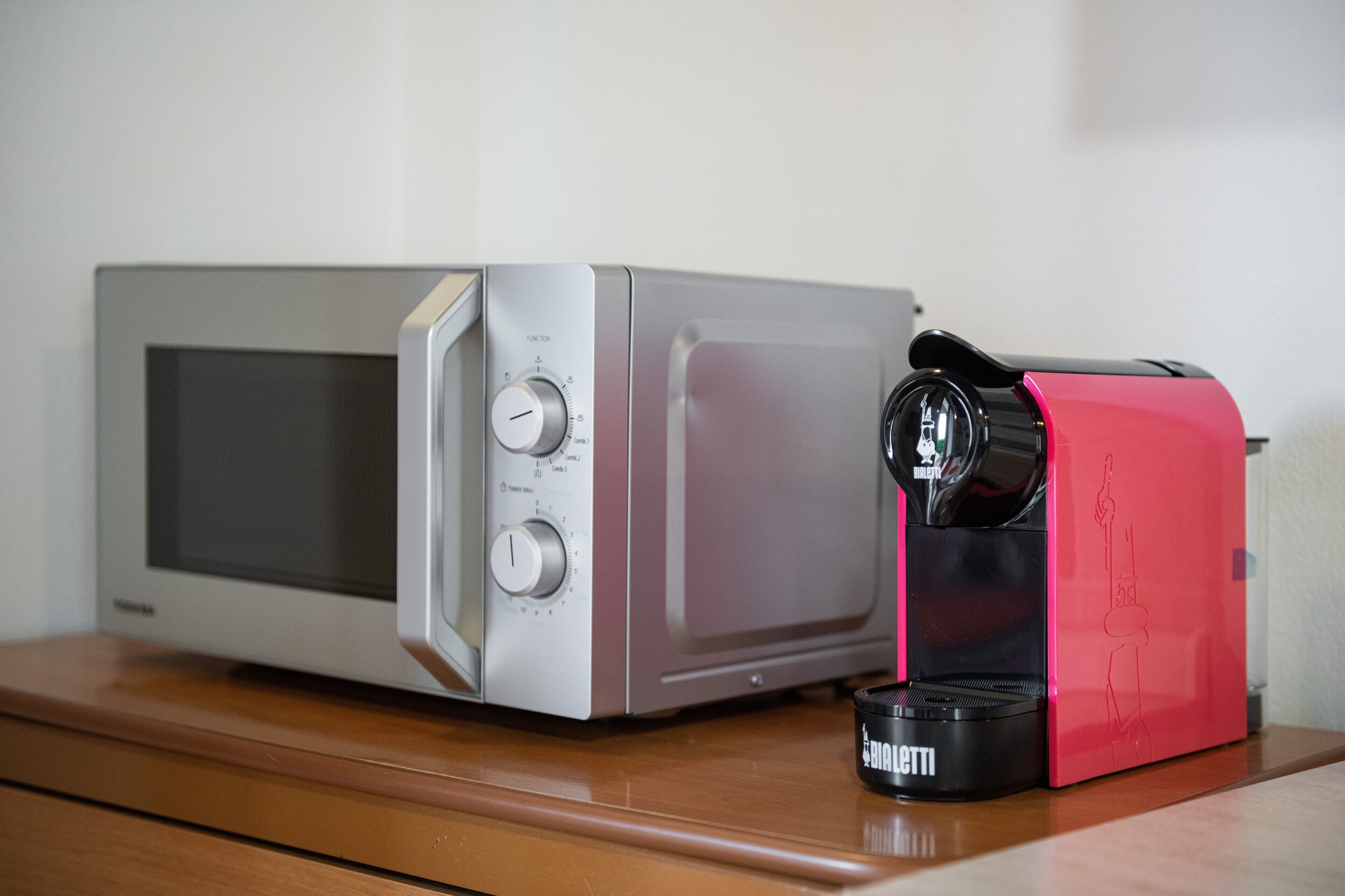 A microwave and a coffee maker on a wooden surface.