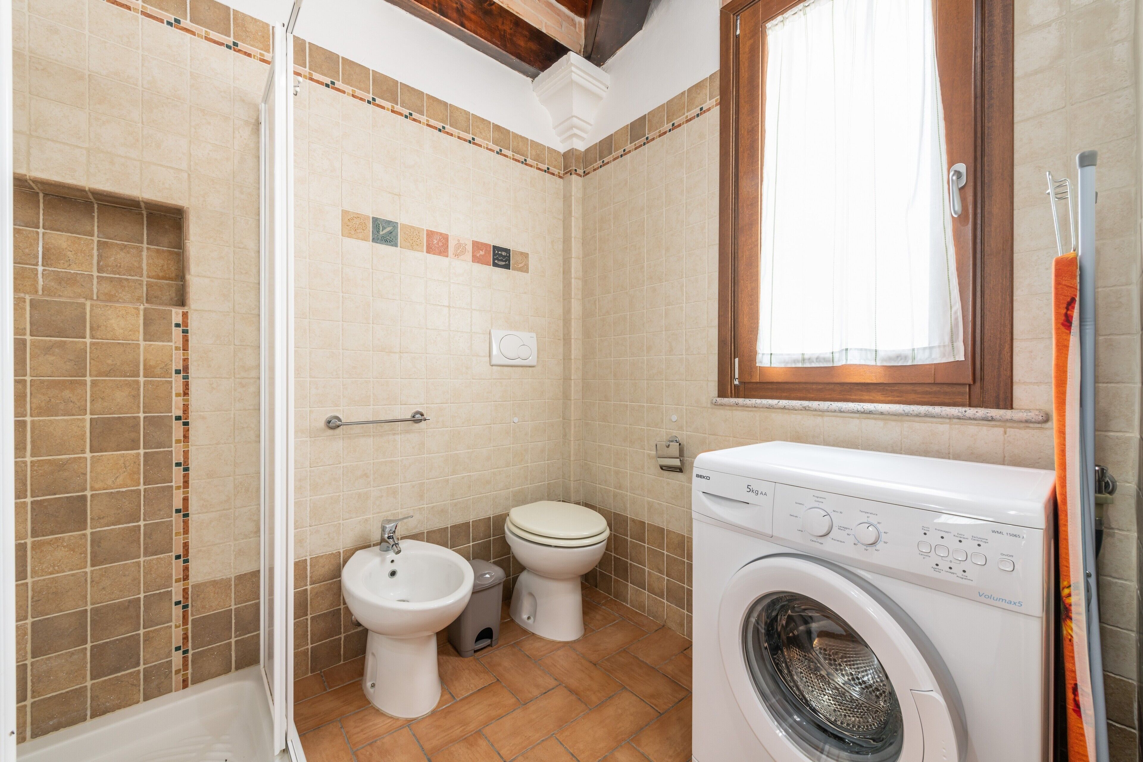 Une salle de bain équipée d’une douche, de toilettes, d’un bidet et d’un lave-linge.