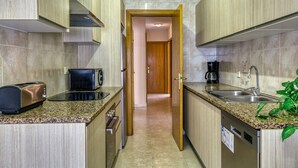 A compact kitchen with granite countertops, a toaster, a coffee maker, and a dishwasher. - Apartment 'La Cargolera' with Sea View, Balcony and Wi-Fi (La Escala)