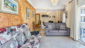 A living room with a sofa, a couch, a chandelier, and framed pictures on the wall. - Apartment 'La Cargolera' with Sea View, Balcony and Wi-Fi (La Escala)