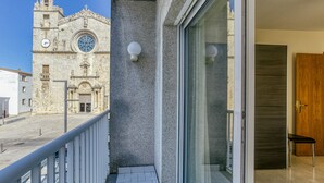 A balcony with a view of a historic church, a glass door, and a wooden door. - Apartment 'La Cargolera' with Sea View, Balcony and Wi-Fi (La Escala)