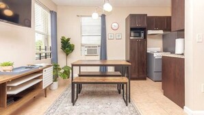 Una cocina compacta con mesa de comedor, armarios empotrados y microondas.