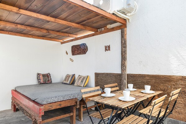 Une pièce comprenant un lit, des bancs en bois servant de sièges et une table avec des tasses et des soucoupes.