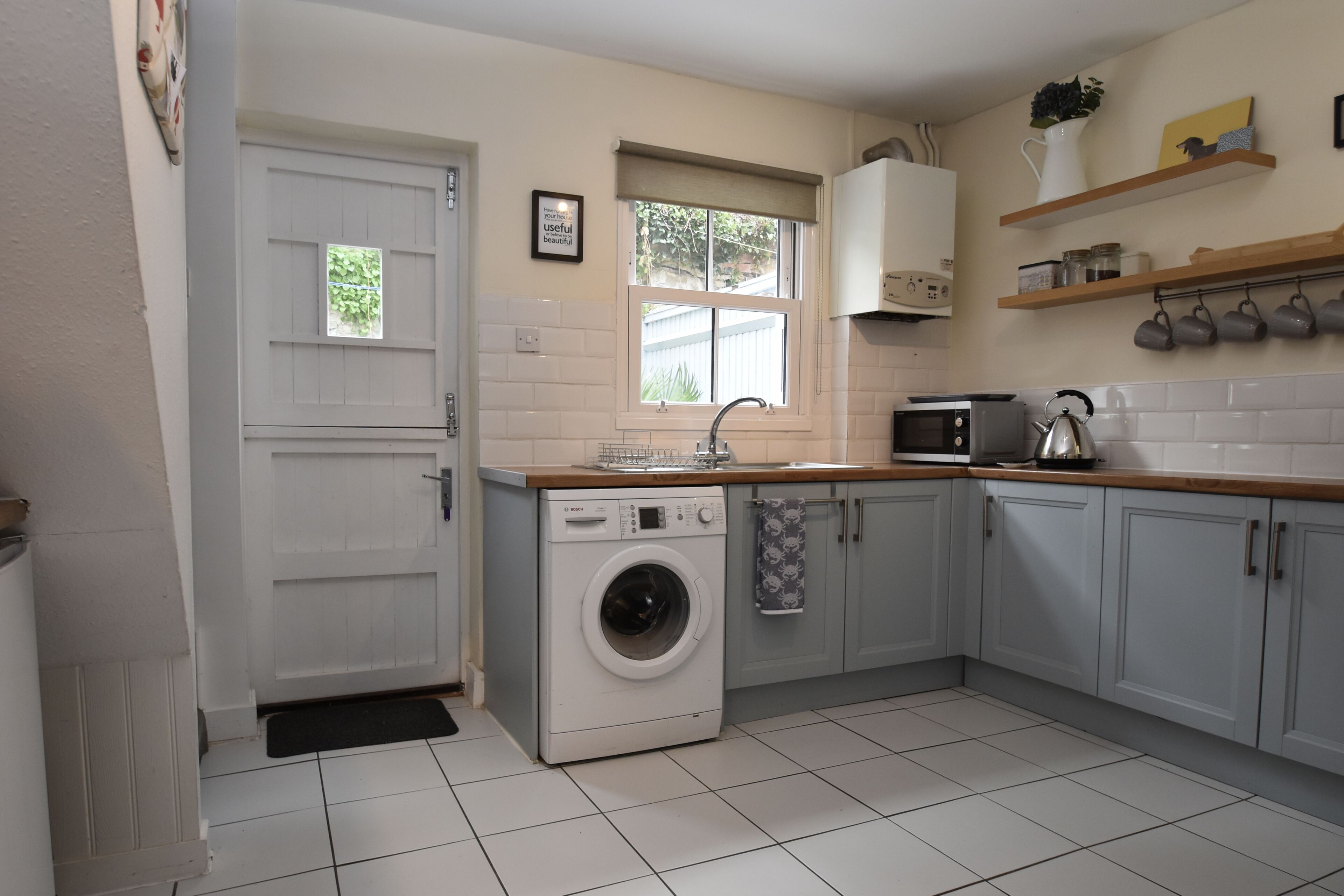 A compact kitchen with a washing machine, a microwave, and a sink.