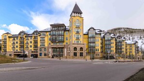 A multi-story hotel with a prominent tower, large windows, and a modern design. - Exceptional Ritz-Carlton Residence by InvitedHome | Ski Valet, Pool, Hot Tub (Vail)