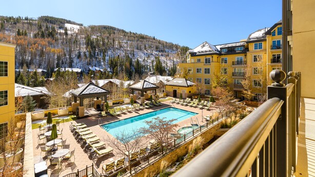 A hotel with a swimming pool, lounge chairs, and a view of a snowy mountain. - Exceptional Ritz-Carlton Residence by InvitedHome | Ski Valet, Pool, Hot Tub (Vail)