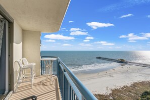 A balcony with white chairs and a view of the beach and pier. - Brighton 1702G Studio Oceanview in Kingston w/Pool (Myrtle Beach)