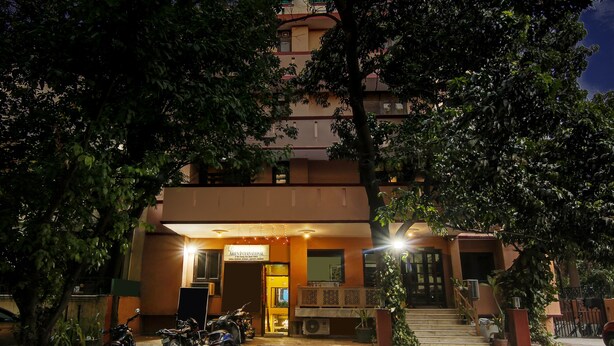 A hotel entrance with a sign reading "Aries International," a staircase leading to the entrance, and a motorbike parked outside. - Itsy Hotels Arien International (New Delhi)