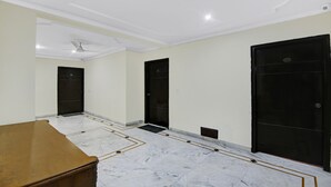 A room with a marble floor, a wooden table, and three black doors. - Itsy Hotels Arien International (New Delhi)