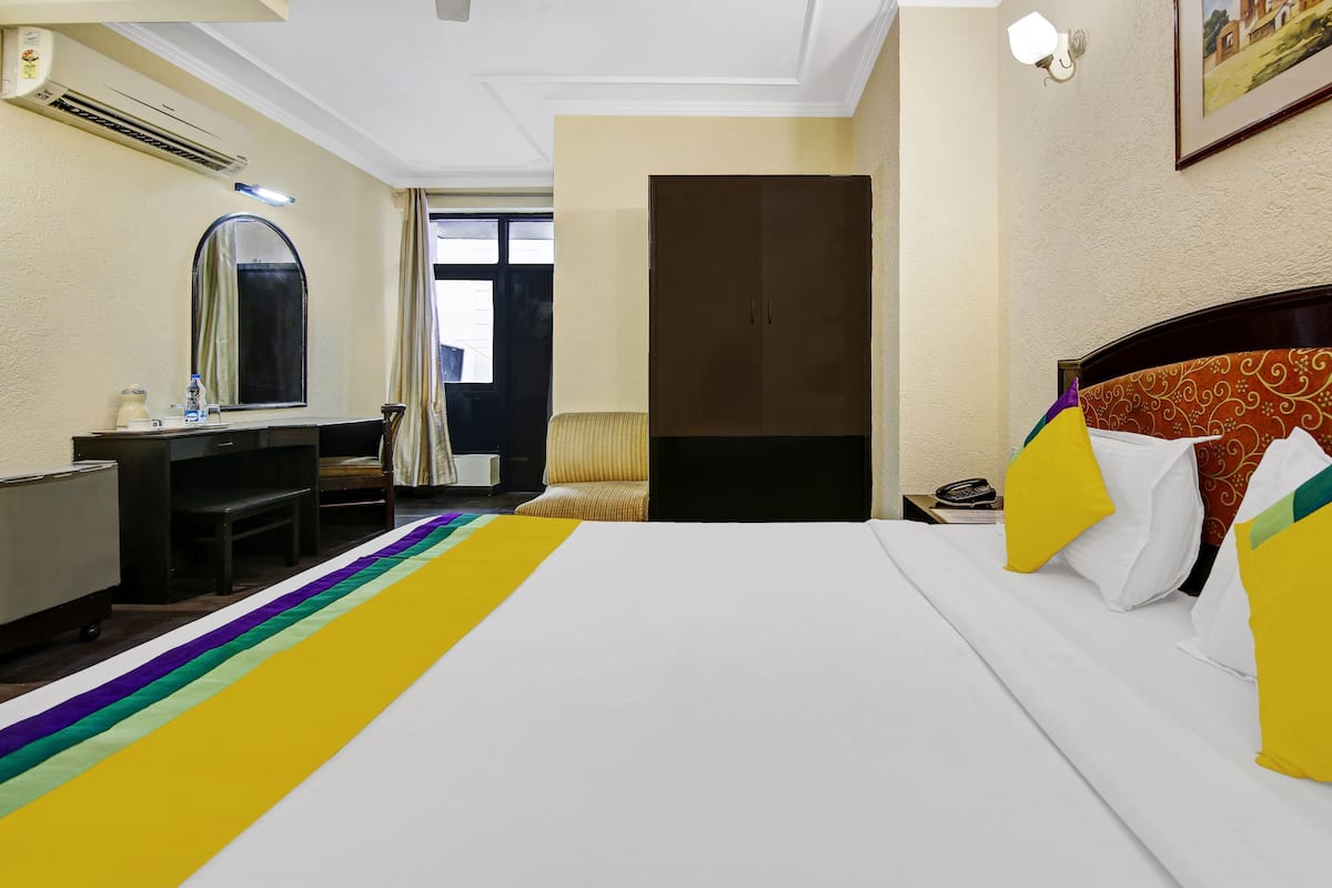 A hotel room with a bed, a desk, a chair, a wardrobe, and a window with curtains.