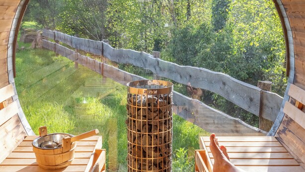 A wooden deck with a circular window overlooking a grassy area and a wooden fence. - Hotel Altitude et Spa Pierre-Percée (Pierre-Percée)