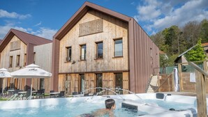 A wooden building with a hot tub and outdoor seating area. - Hotel Altitude et Spa Pierre-Percée (Pierre-Percée)