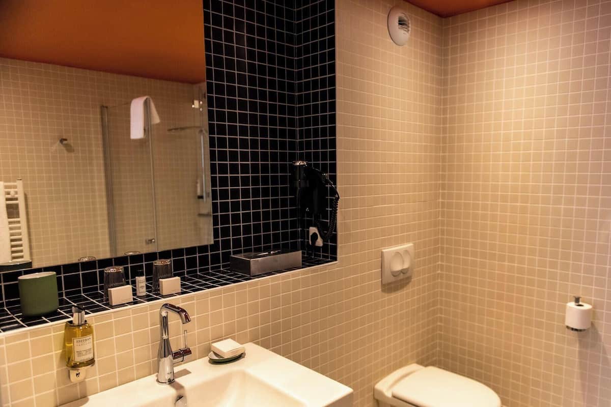 Un baño con lavamanos, espejo y retrete.