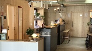 A reception area with a wooden interior, a reception desk, and a bar area with stools. - Hotel Altitude et Spa Pierre-Percée (Pierre-Percée)