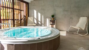 A modern indoor swimming pool with a hot tub, surrounded by large windows and wicker chairs. - Hotel Altitude et Spa Pierre-Percée (Pierre-Percée)